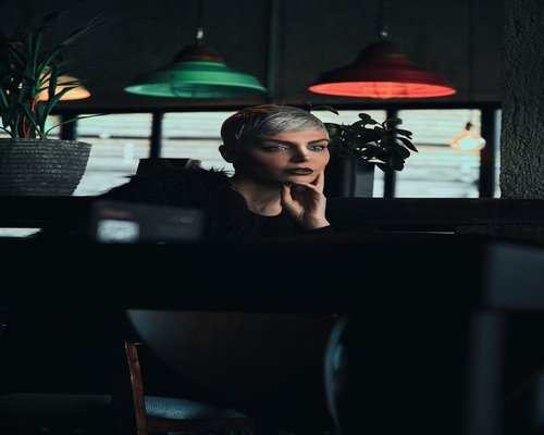 Woman looking away from her laptop, resting her eyes while sitting in a cafe